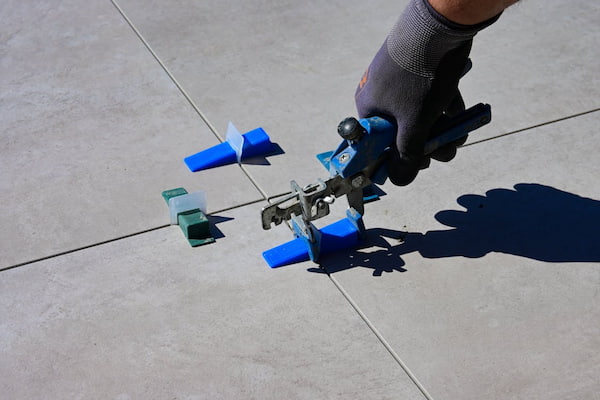 hand in a glove using a tile levelling tool
