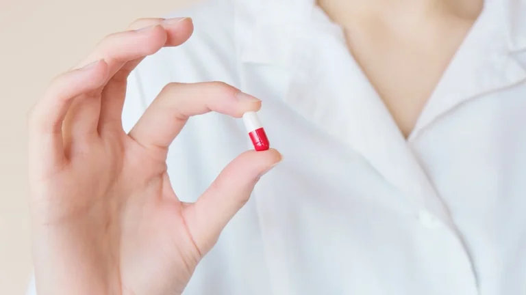 a person in white clothes holding a capsule