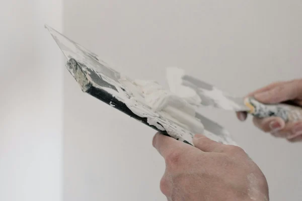 a man wearing white gloves applying wall putty