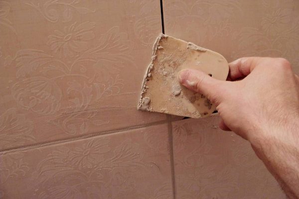 a-person-is-caulking-the-tiles