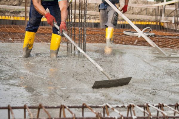 two bricklayers at work on a construction site during the laying of concrete to build the foundations of a house